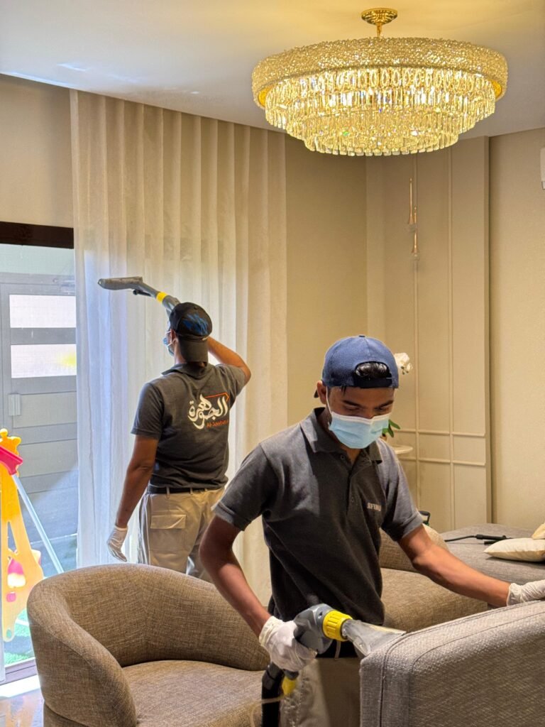 عامل تنظيف كنب في البحرين أثناء تنظيف غرفة المعيشة باستخدام أجهزة الشفط